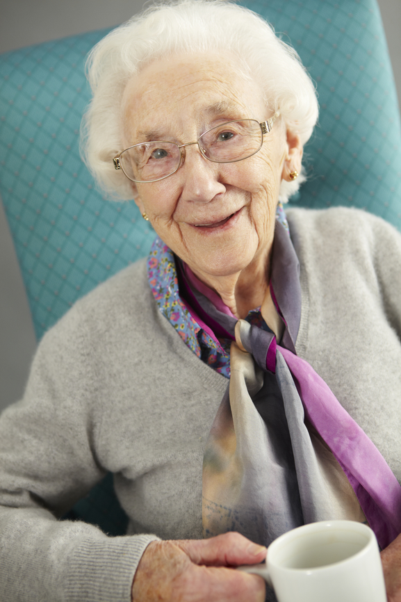 Senior Woman Relaxing In Chair With Hot Drink